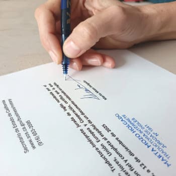 La imagen muestra la mano de Marta Mozo firmando al pie de una traducción junto a su sello de traductora jurada para certificar que la traducción es fiel al documento original.